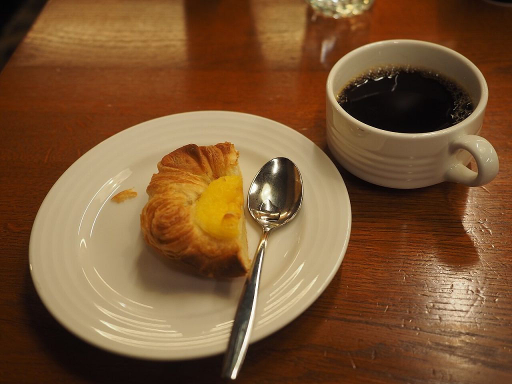 Wienerbrød og en kop kaffe på et træbord